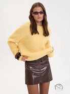 Winter loose long wool alpaca sweater in yellow with brown cuffs over leather skirt