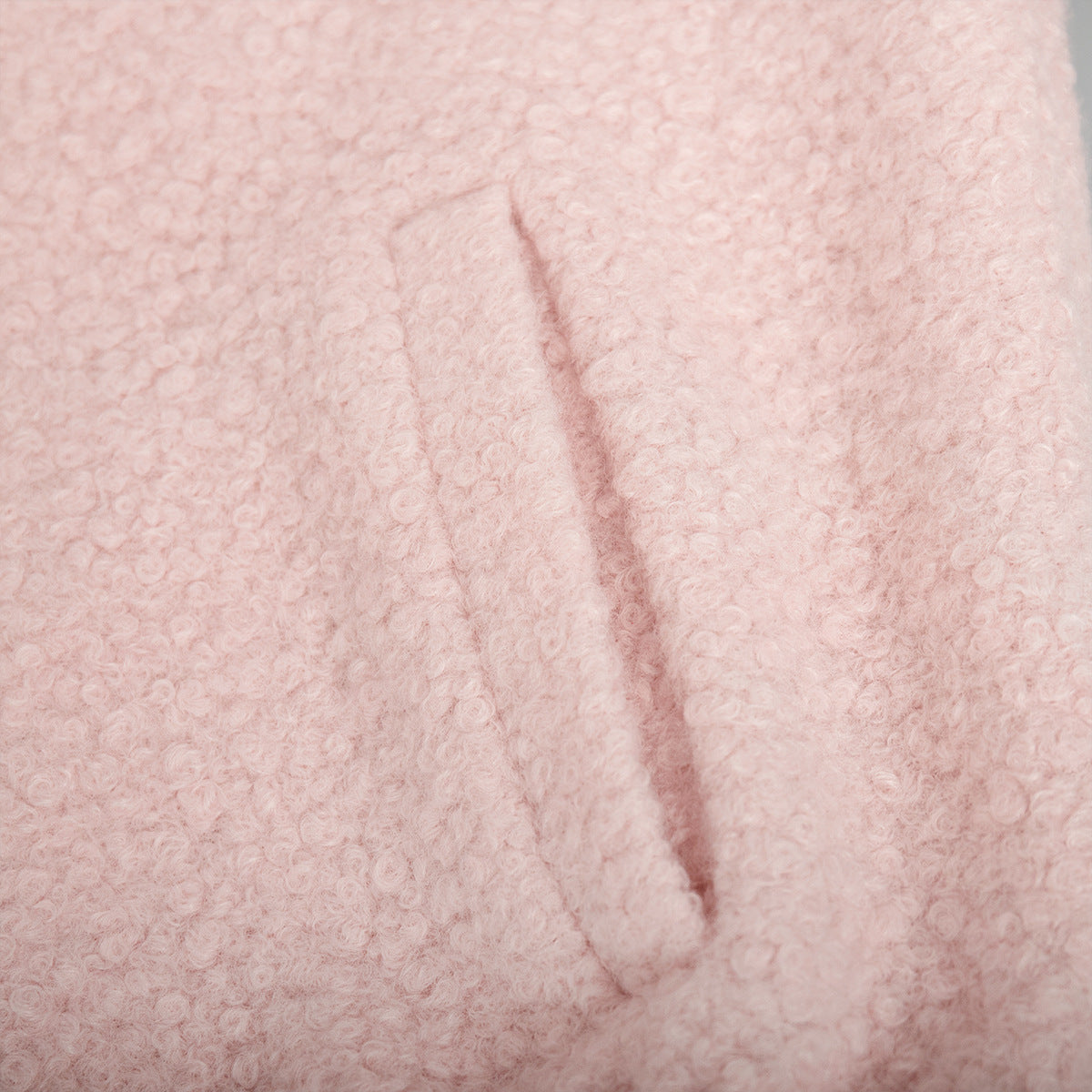 Pink short furry coat showcasing pink bouclé fabric with pocket detail