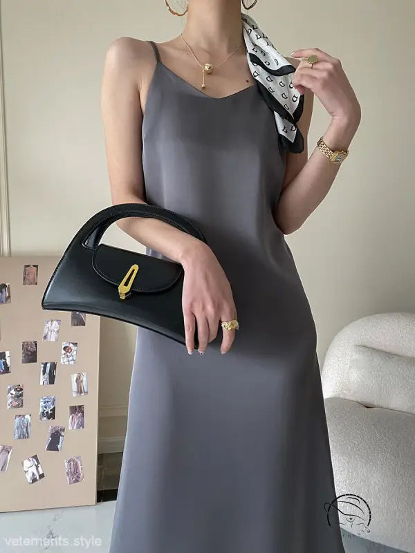 Obsidian black leather handbag with gold hardware on olive green acetate satin dress