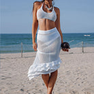 White crocheted two-piece beachwear set featuring a crop top and ruffled skirt, ideal for summer fashion