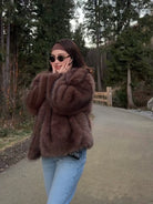 Elegant faux fur fox coat in brown black with oversized collar, paired with light blue jeans