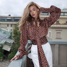 Elegance Polka Dot Shirt with ruffled sleeves and tie waist on brown background