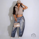 Person in casual dirty denim pants, beige cropped jacket, LA cap, nude handbag