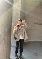 Beige faux fur oversized coat with black leather accents and floral headband