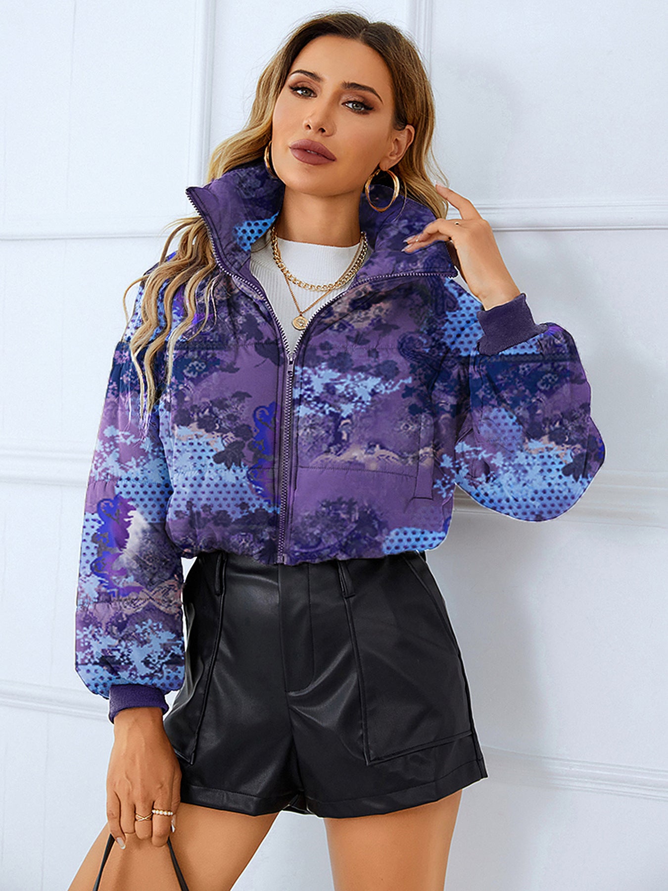 Woman in a patterned puffer jacket and black shorts, showcasing elegant thermal fashion ملابس