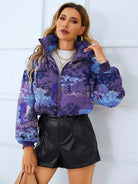 Woman in a patterned puffer jacket and black shorts, showcasing elegant thermal fashion ملابس