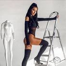 Woman in gorgeous mesh stitching jumpsuit and thigh-high boots posing by ladder
