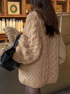 Beige cable knit long sleeve oversized cardigan with black leather tote bag
