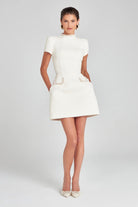Elegant white mini dress with high neckline and pockets, perfect for modern fashion lovers