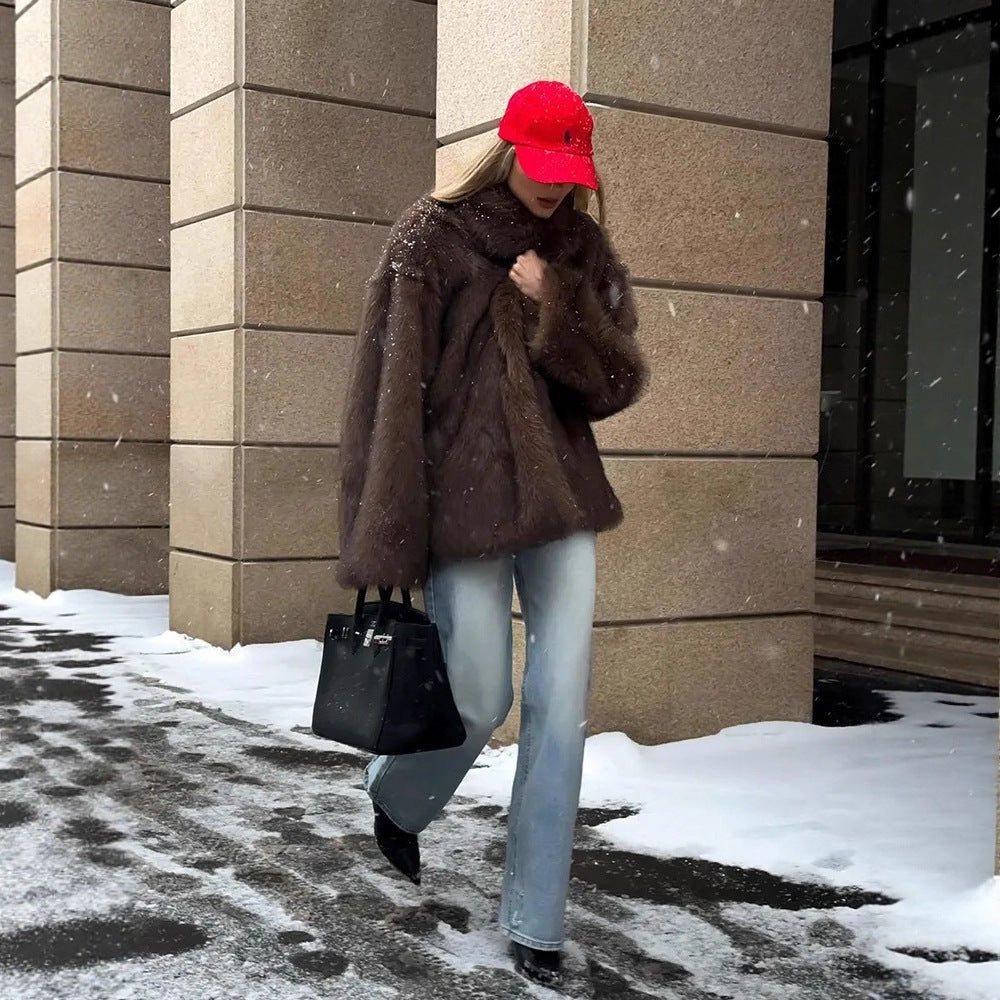 Fashionable warm faux fur coat with black leather handbag and silver hardware