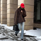 Fashionable warm faux fur coat with black leather handbag and silver hardware