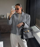 Langry fashion gray wool blazer with oversized sleeves and large lapels, paired with black leather handbag featuring silver hardware