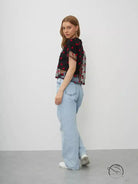 Elegant faux cotton short top: model in sheer floral blouse and light blue jeans against plain backdrop