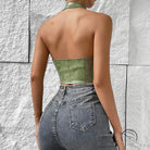 Woman in solid color halter faux leather vest with distressed jeans