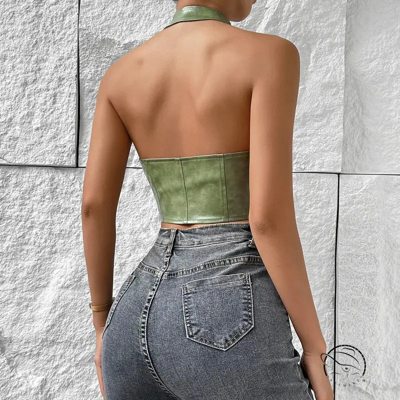 Woman in solid color halter faux leather vest with distressed jeans