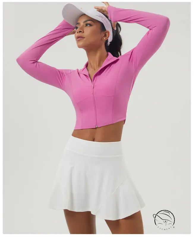 Woman in long sleeve pink zipper sports jacket and white pleated tennis skirt
