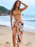 Woman in gorgeous split bikini with fringed top and floral sarong on beach