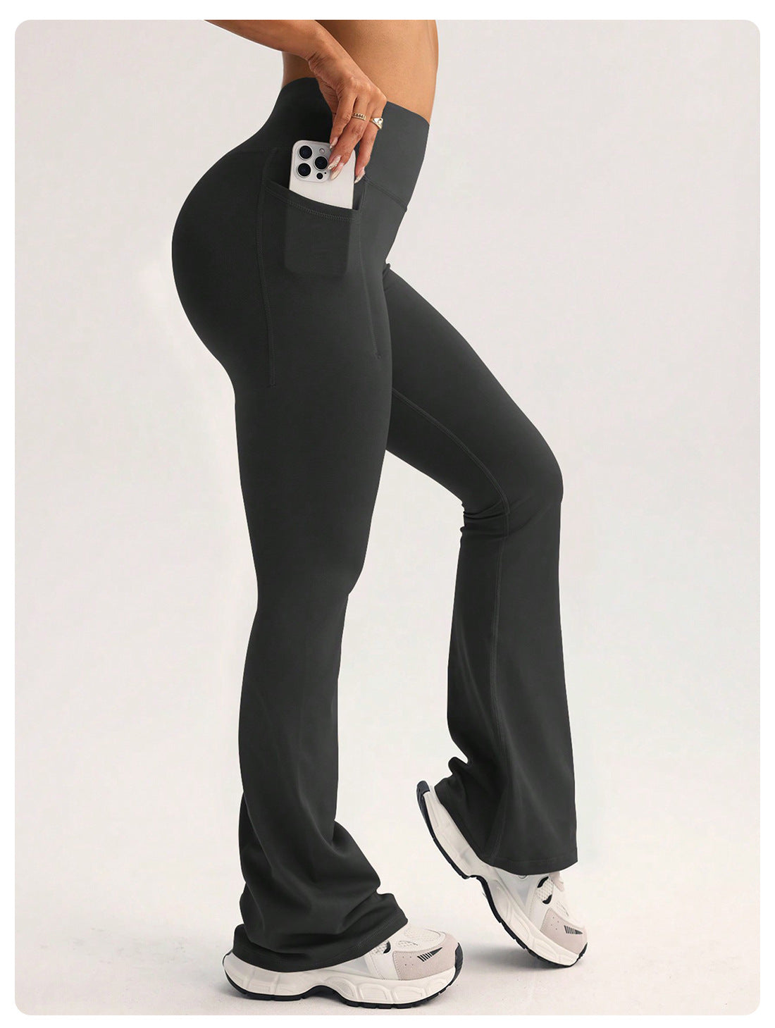 Black high-waisted flared langry yoga pants with side pocket holding white smartphone