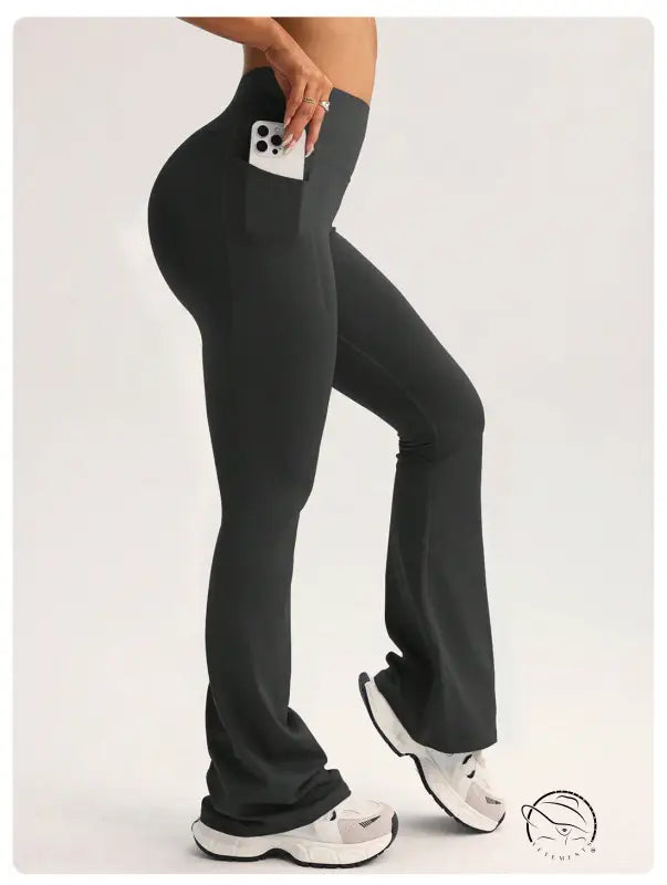 Black high-waisted flared langry yoga pants with side pocket holding smartphone