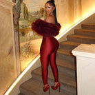 Red patent leather off-shoulder long sleeve furry jumpsuit with fur trim, gloves, heels