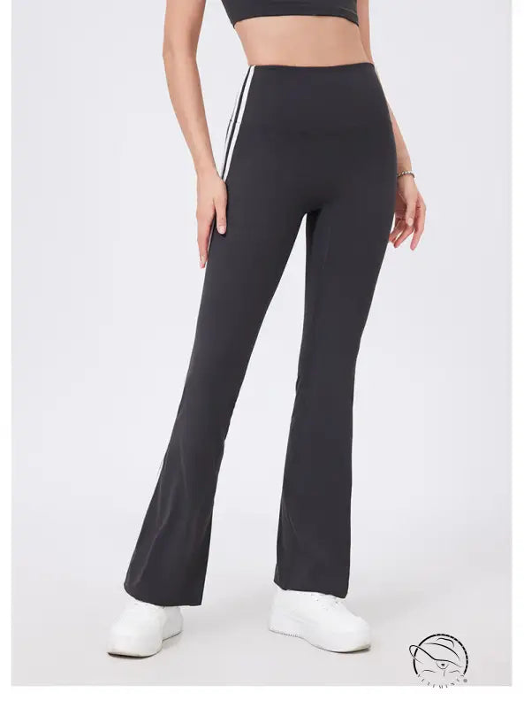 Black high-waisted flared yoga pants with white stripes and peach hip raise