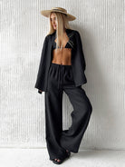 Woman in black linen outfit with straw hat, showcasing stylish langry fashion ملابس