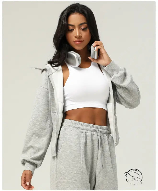 Woman in gray sweatsuit and white sports bra wearing casual cardigan sweater