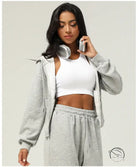 Woman in gray sweatsuit and white sports bra wearing casual cardigan sweater
