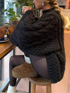 Black cable knit long sleeve sweater with ribbed cuffs and white socks