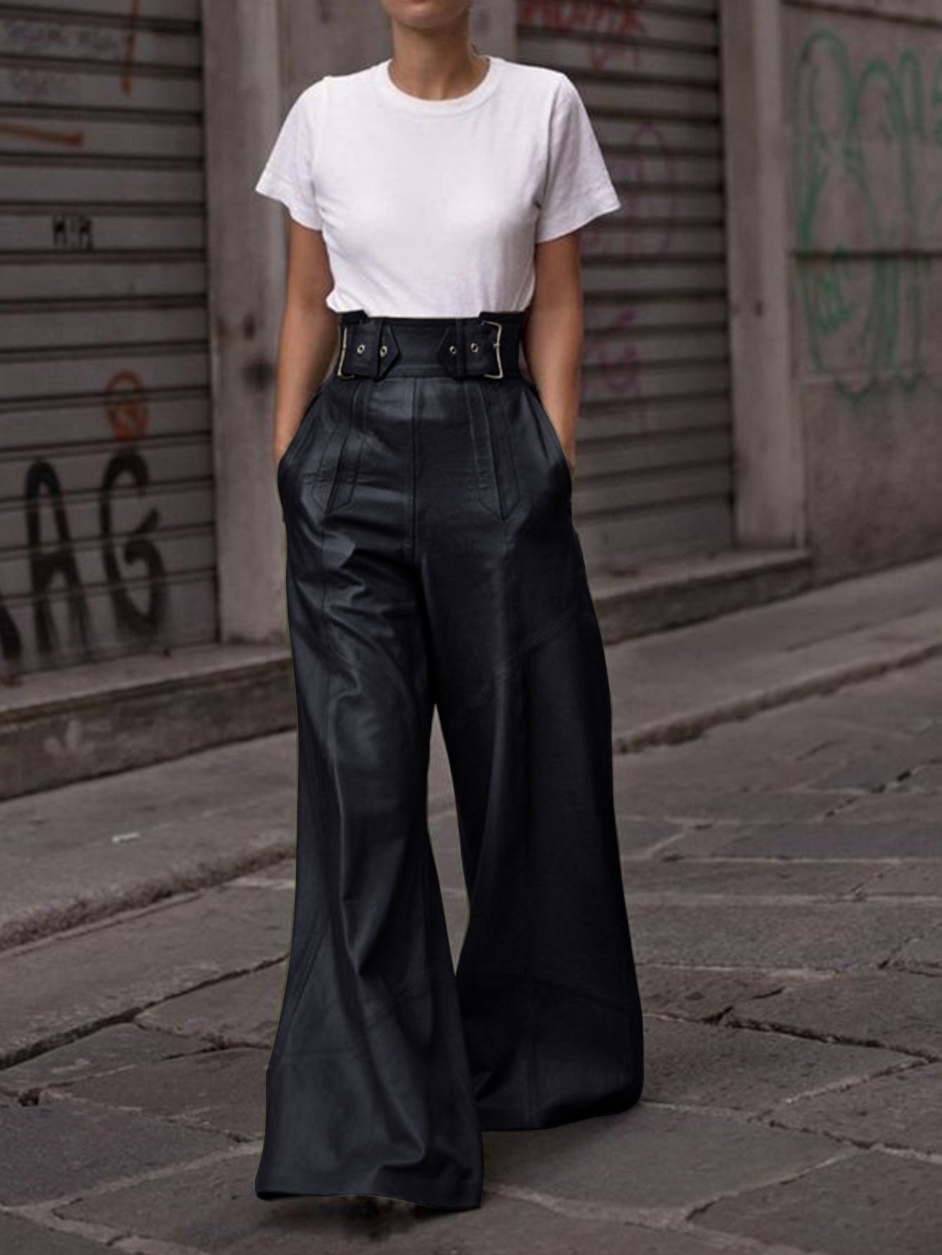 Person wearing white T-shirt and black faux leather bell bottom pants in fashion style