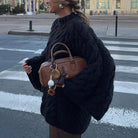 Brown leather handbag with gold hardware and white tassel charm for long sleeve fashion