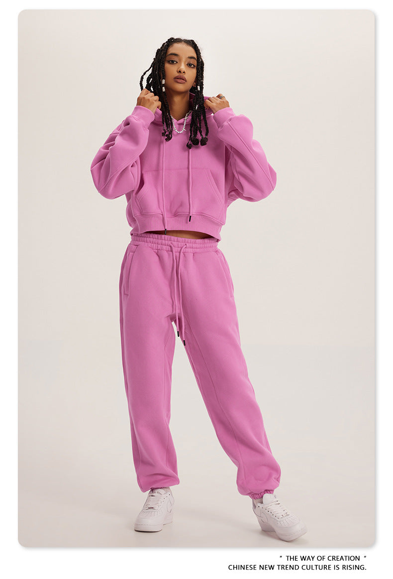 Pink sweatsuit with hoodie and joggers, styled with white sneakers for trendy fashion ملابس
