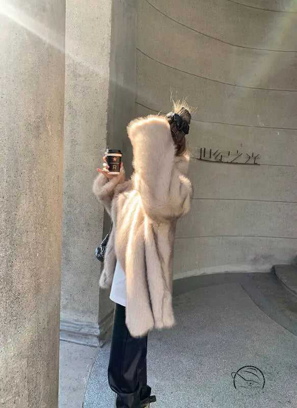 Cream-colored faux fur hooded jacket with black leather boots
