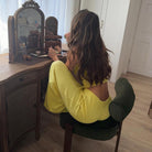 Woman in Langry fashion ملابس yellow jumpsuit applying makeup at vanity