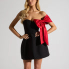 Black strapless cocktail dress with red bow accent, a stunning piece for glamorous fashion