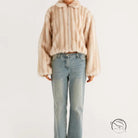 Beige faux fur cropped jacket with hood and striped pattern over light wash denim flared jeans