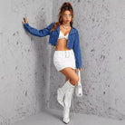 Woman wearing slimming short denim coat, white mini skirt, and knee-high boots