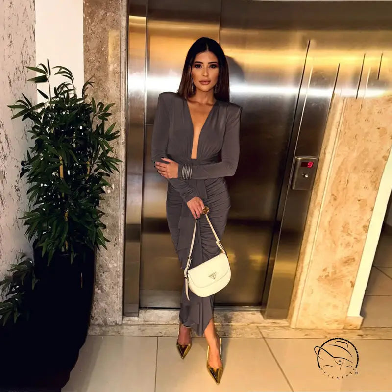 Elegant slim evening dress in gray pleated langry fashion with deep neckline, long sleeves, paired with gold high heels