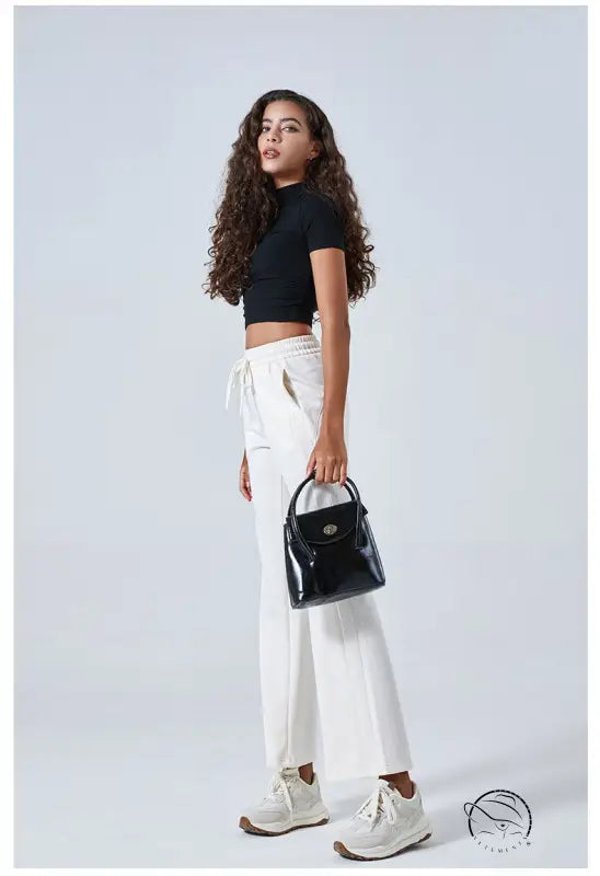 Woman in black crop top, summer air layer drawstring pants, sneakers, handbag