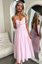 Pink spaghetti-strap midi dress with button details, perfect for elegant fashion occasions