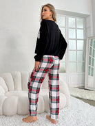 Woman wearing winter long sleeve trousers home wear set with black top and plaid pants