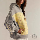 Yellow quilted hoodie with embroidery stitching, floral accents, gray sleeves