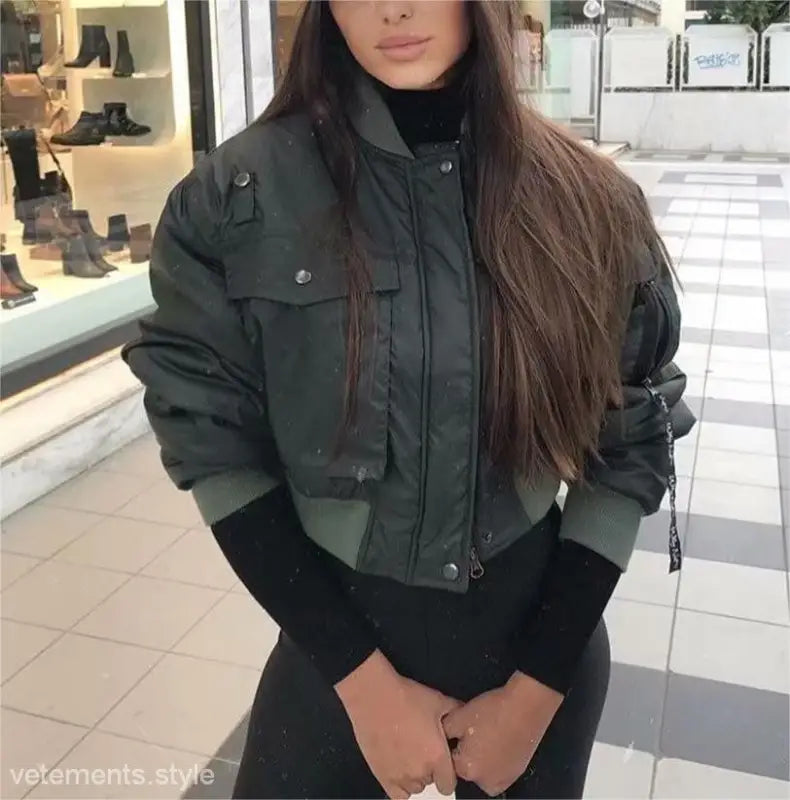 Dark green bomber jacket with pockets and zippers, styled over a black top