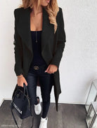 Black trench coat over dark outfit, paired with white sneakers and Balenciaga handbag