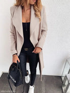 Beige trench coat layered over a black outfit with white sneakers for fall and winter