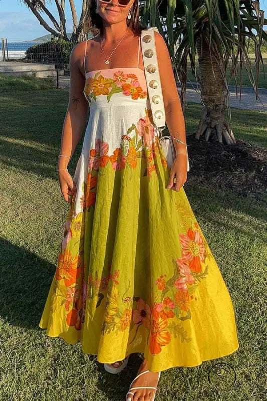 Colorful floral maxi dress with a white bodice and yellow skirt adorned with orange and pink flower patterns.