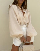 Cream-colored lantern sleeve shirt paired with white shorts and matching handbag