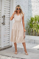 Cream-colored tiered midi dress with V-neckline showcased with Elegant Navy Blue Waist Pleated Dress