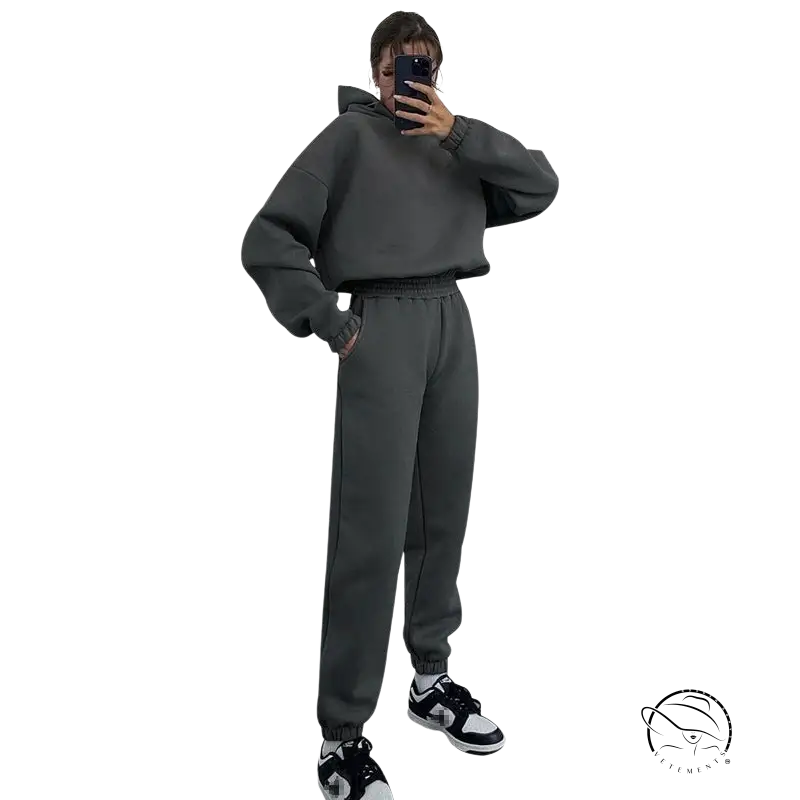 Person in hooded long sleeve sweater taking mirror selfie in gray sweatsuit