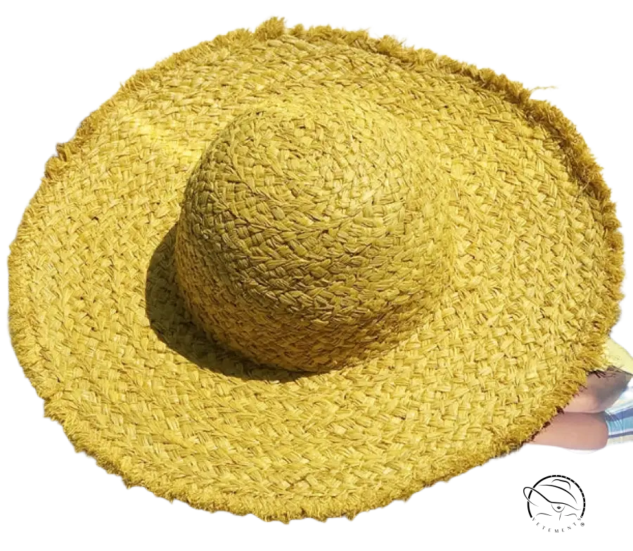 Woven yellow straw broad brimmed hat with frayed edge and beige ribbon band